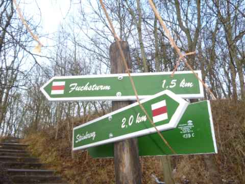 Ein Wegweiser am Parkplatz am Zugang zur Weihestätte zeigt den roten Wanderweg mit Hinweis auf den Fuchsturm nach 1,5 km! Da meint man wohl 150 m!