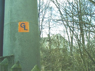 Bild 255: Das letzte neu aufgemalte GL-Symbol am Zugangsweg zu 1 a. Im Hintergrund sieht man das ehemalige Gebäude der Brauckmannschule.